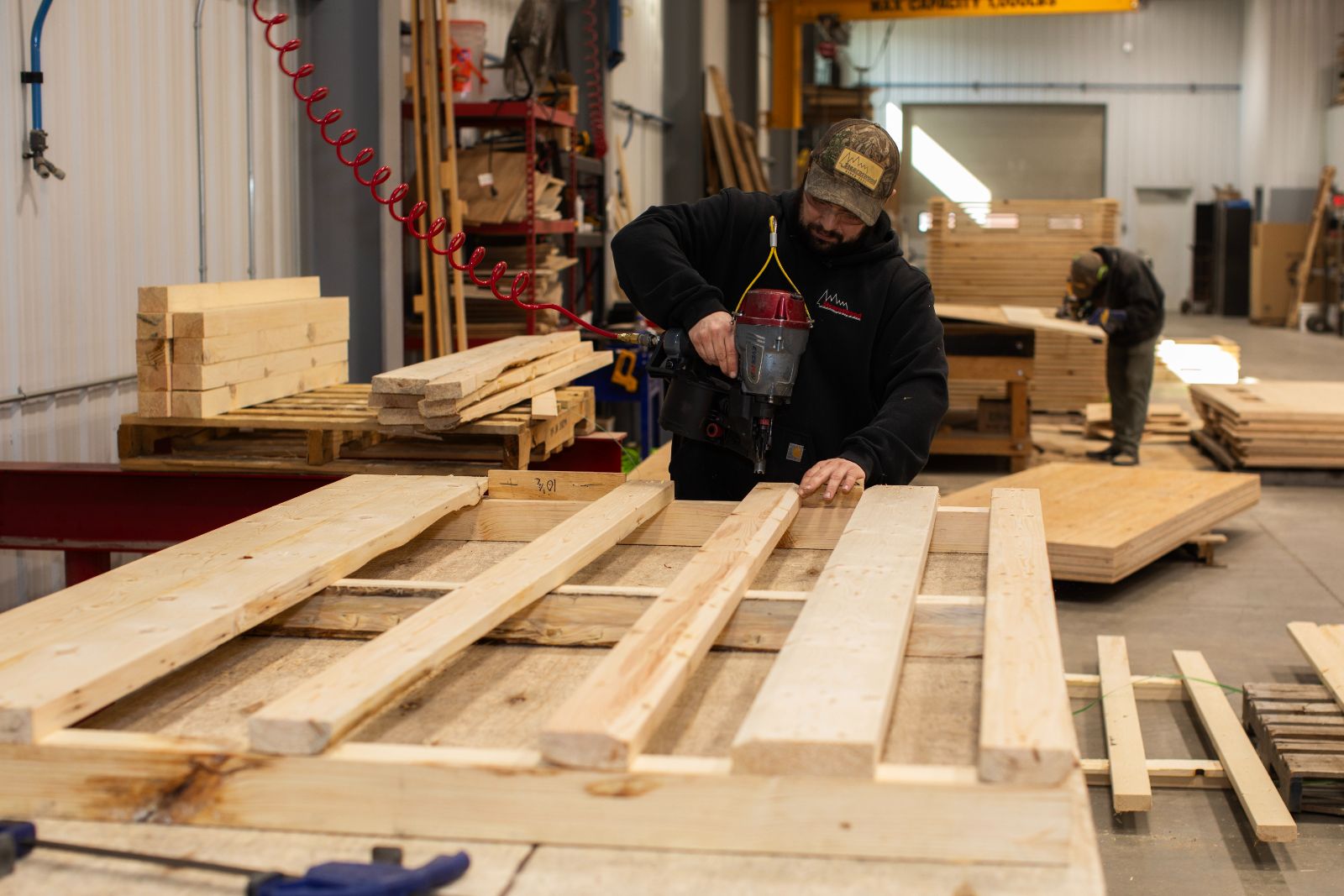 a man drilling wooden planks onto a frame