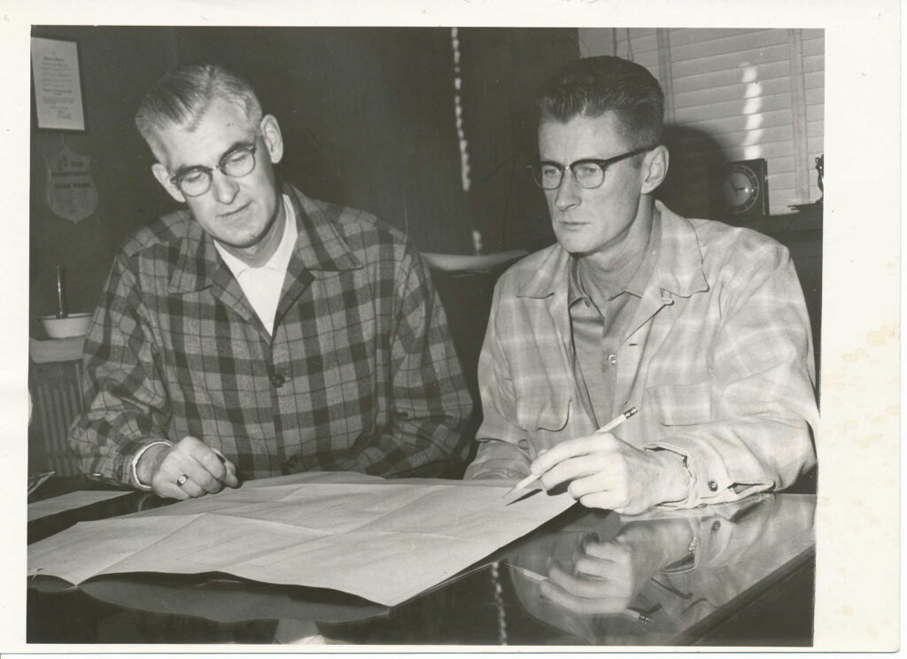 robert and ned stearns look over a sheet of paper in the 1950s